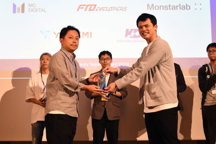 KDDIアジャイル開発センター株式会社のエンジニアリングマネージャーである吉村知久氏がトロフィーを受け取っている様子